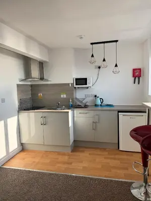 a kitchen with white cabinets and a sink at The Charlton - Aparthotel in Blackpool