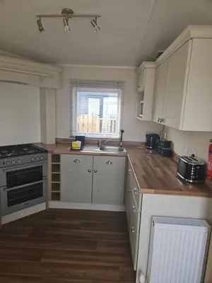 a kitchen with white cabinets and a sink at Lytham Luxe 6 Birth Caravan in Weeton