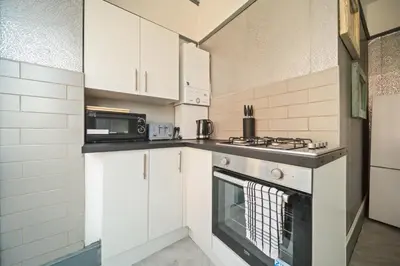a kitchen with white cabinets and a stove top oven at Spacious, Central Townhouse with Hot Tub & Free Parking in Lytham St Annes