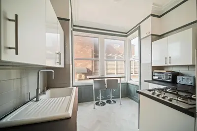a kitchen with white cabinets and a large window at Spacious, Central Townhouse with Hot Tub & Free Parking in Lytham St Annes