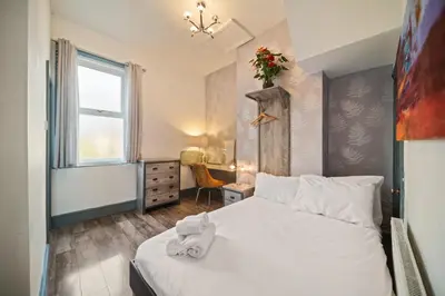 a bedroom with a white bed and a window at Spacious, Central Townhouse with Hot Tub & Free Parking in Lytham St Annes