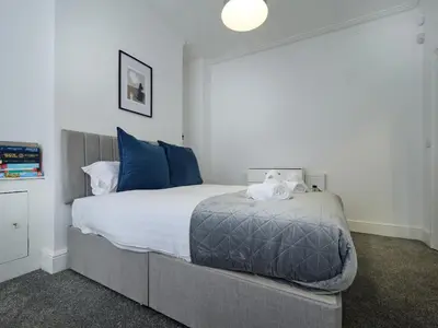 a bedroom with a large bed with blue pillows at Woodcroft House - Air Host & Stay - 4 Bedrooms in Liverpool