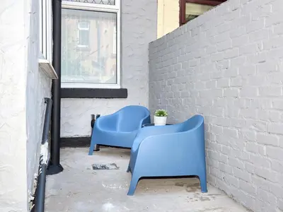 two blue chairs sitting next to a brick wall at Woodcroft House - Air Host & Stay - 4 Bedrooms in Liverpool
