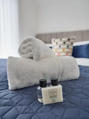 a bed with a towel and a bottle of facial kit at Woodcroft House - Air Host & Stay - 4 Bedrooms in Liverpool