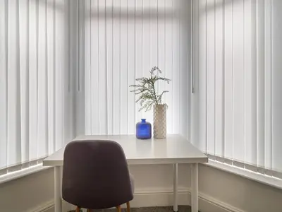 a table with a blue vase and a chair in front of windows at Woodcroft House - Air Host & Stay - 4 Bedrooms in Liverpool