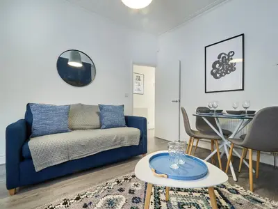 a living room with a blue couch and a table at Woodcroft House - Air Host & Stay - 4 Bedrooms in Liverpool