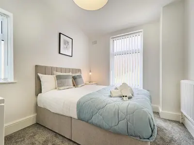 a bedroom with a bed with a teddy bear on it at Woodcroft House - Air Host & Stay - 4 Bedrooms in Liverpool