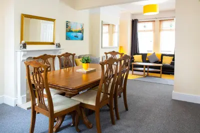 a dining room with a wooden table and chairs at Newly Launched 3 Bedroom House with Free Parking in Litherland