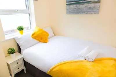 a small bedroom with a bed and a window at Newly Launched 3 Bedroom House with Free Parking in Litherland