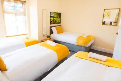 a room with three beds and a window at Newly Launched 3 Bedroom House with Free Parking in Litherland