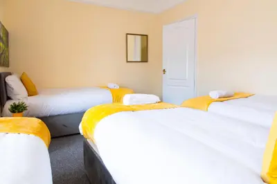 a room with three beds with yellow blankets at Newly Launched 3 Bedroom House with Free Parking in Litherland