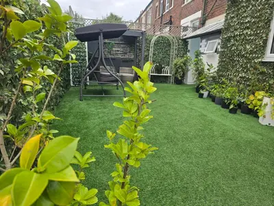 a small garden with green grass and a grill at Ensuite room with private entrance and private garden in Blackpool