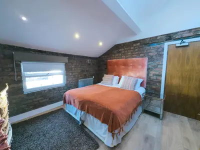 a bedroom with a bed and a brick wall at Richmond Apartment in Liverpool