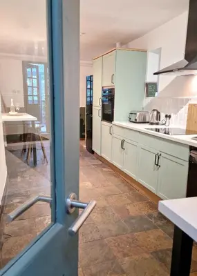 a kitchen with white cabinets and a door open at Historic 17th-Century Cottage with Hot Tub in Charming Heysham in Heysham