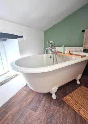 a white bath tub sitting in a room at Historic 17th-Century Cottage with Hot Tub in Charming Heysham in Heysham