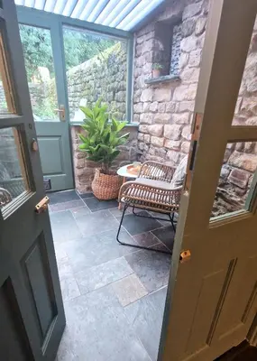 an open door to a patio with a chair and a plant at Historic 17th-Century Cottage with Hot Tub in Charming Heysham in Heysham