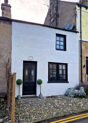 a white house with a black door and windows at Historic 17th-Century Cottage with Hot Tub in Charming Heysham in Heysham