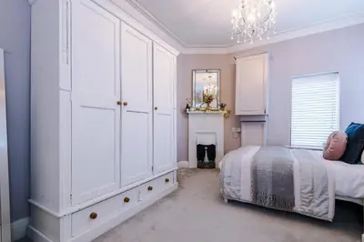 a white bedroom with a bed and a chandelier at Stylish 1-Bed Apartment in St. Annes in Lytham St Annes