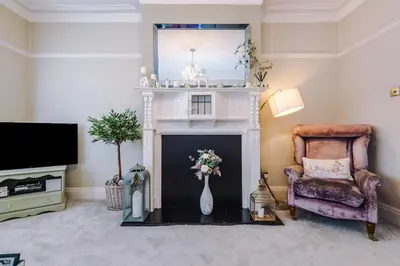 a living room with a fireplace with a chair and a mirror at Stylish 1-Bed Apartment in St. Annes in Lytham St Annes