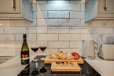 a bottle of wine and wine glasses on a kitchen counter at Stay With Alexandra 2 Free Parking - high speed Free Wifi close to stadiums in Liverpool
