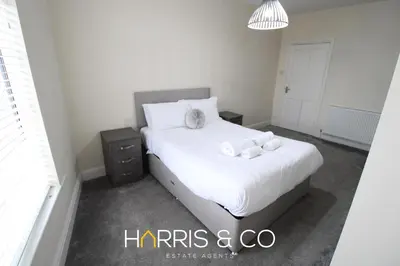 a bedroom with a bed with white sheets and towels at Light House View in Fleetwood