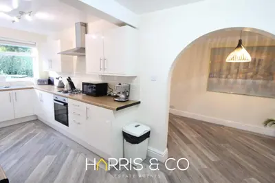 a kitchen with white cabinets and a wooden floor at Poolfoot Villas in Thornton