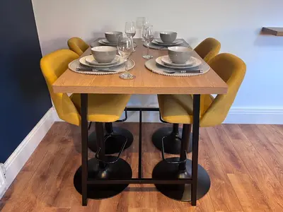a wooden table with yellow chairs and plates and wine glasses at Waterside Cottage in Preston