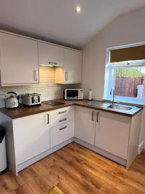 a kitchen with white cabinets and a sink and a window at Waterside Cottage in Preston