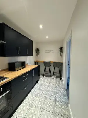 a kitchen with black cabinets and a tile floor at Zetland House Apartment - First floor with garden and parking in Southport