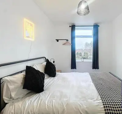 a bedroom with a bed with black pillows and a window at Zetland House Apartment - First floor with garden and parking in Southport