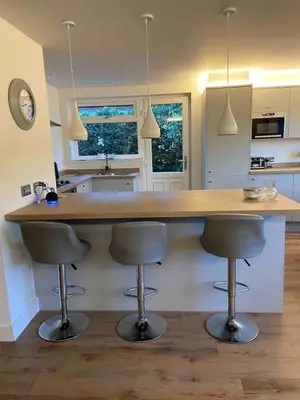 a kitchen with a counter with three bar stools at Holiday Bungalow in Arnside in Arnside