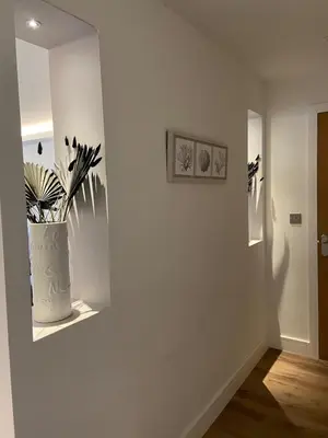 a white hallway with a vase with a plant in it at Holiday Bungalow in Arnside in Arnside