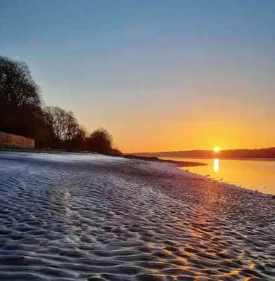a sunset on the shore of a beach at Holiday Bungalow in Arnside in Arnside