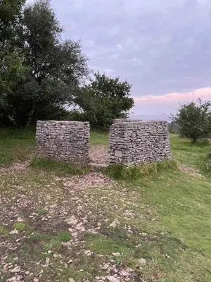 two stone walls in a field with trees in the background at Holiday Bungalow in Arnside in Arnside