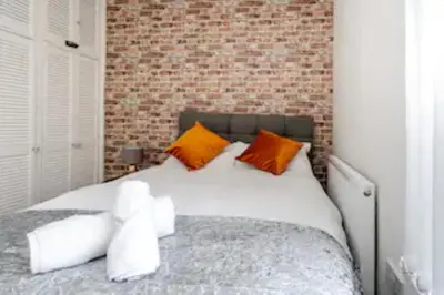a bedroom with a bed with orange and white pillows at Providence Luxury Apartment in Liverpool