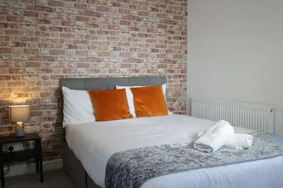 a bedroom with a bed with a brick wall at Providence Luxury Apartment in Liverpool