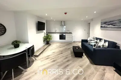 a living room with a blue couch and a kitchen at Kittiwake in Fleetwood