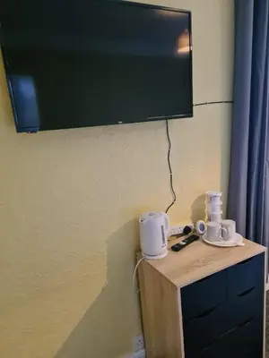 a flat screen tv hanging on a wall with two cups at The Eagle and Child in Garstang
