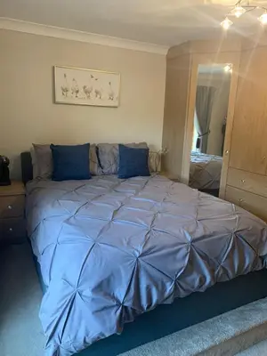 a large bed in a bedroom with a blue comforter at Shore Cottage A traditional cosy cottage in Wilpshire