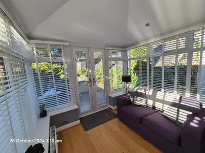 a living room with a purple couch and windows at Shore Cottage A traditional cosy cottage in Wilpshire