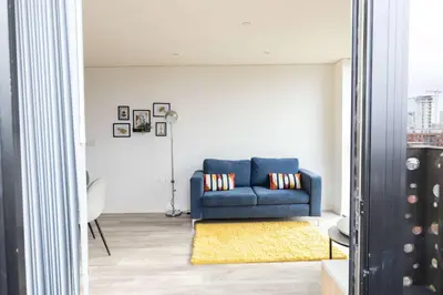 a living room with a blue couch and a yellow rug at Spacious 1 Bedroom Apartment in Central Liverpool in Liverpool