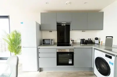 a kitchen with gray cabinets and a washer and dryer at Spacious 1 Bedroom Apartment in Central Liverpool in Liverpool