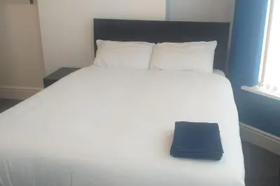 a large white bed with a blue pillow on it at Liverpool 3-Bed House - Sleeps 6 in Liverpool