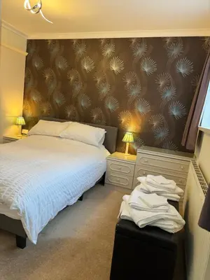 a bedroom with a bed and two night stands with lamps at Linden Ave Bungalow in Thornton