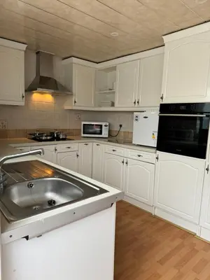 a kitchen with white cabinets and a stainless steel sink at Linden Ave Bungalow in Thornton