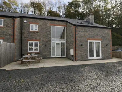 a brick cottage with a picnic table on a patio at Edgemere Cottage in Grange Over Sands