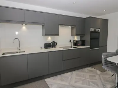 a kitchen with gray cabinets and a sink at Edgemere Cottage in Grange Over Sands