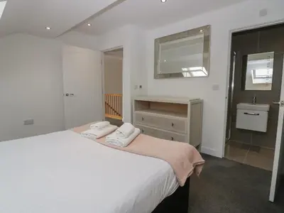 a white bedroom with a bed and a sink at Edgemere Cottage in Grange Over Sands