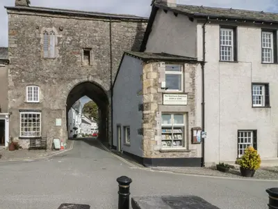 an old stone building with an archway next to a street at Edgemere Cottage in Grange Over Sands