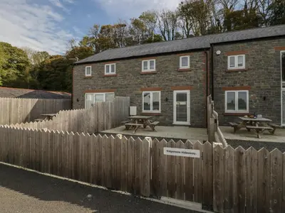 a brick house with a wooden fence and a picnic table at Edgemere Hideaway in Grange Over Sands